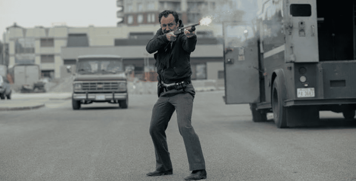 A man in a black outfit is gripping a gun